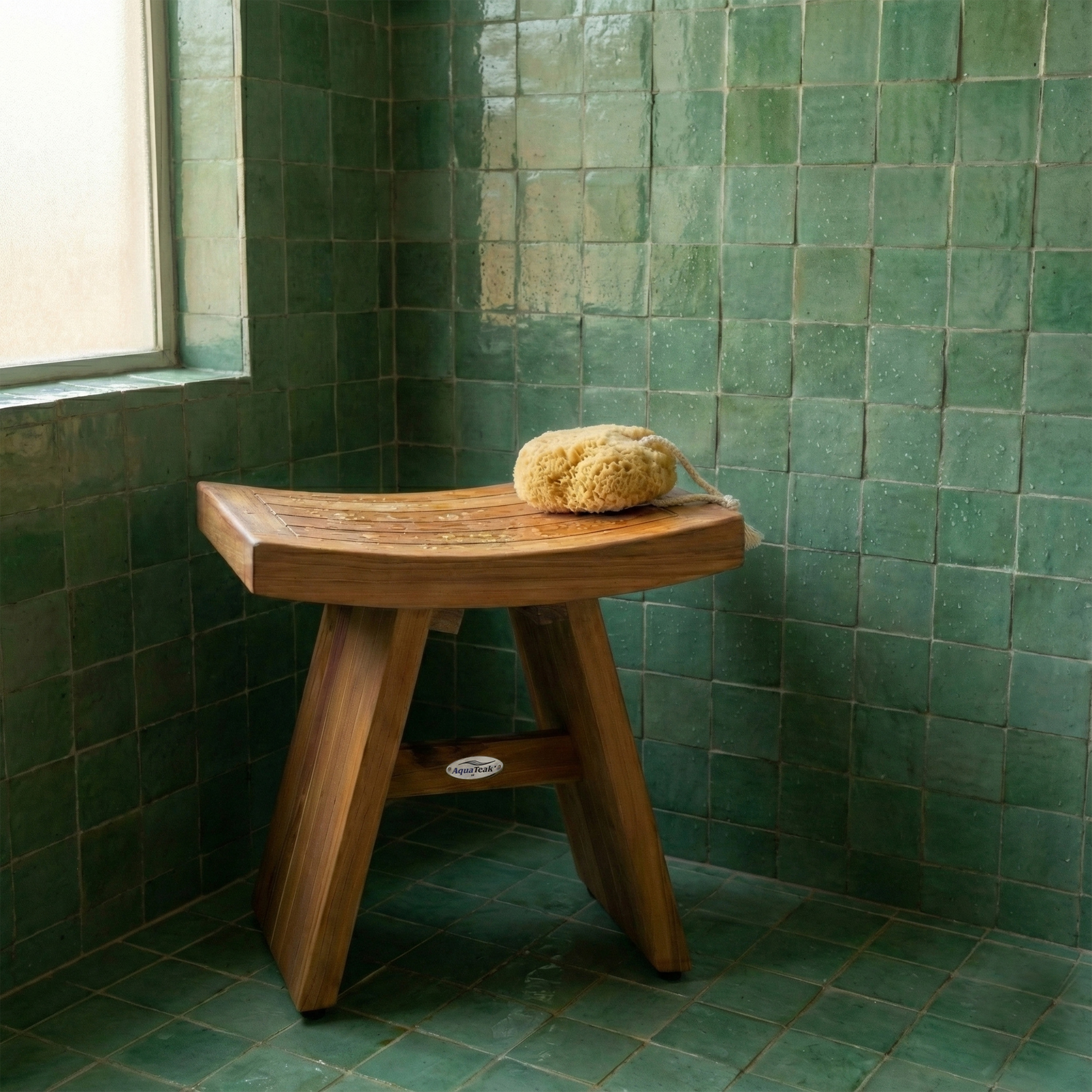 Curved AquaTeak shower bench in a green tiled bathroom